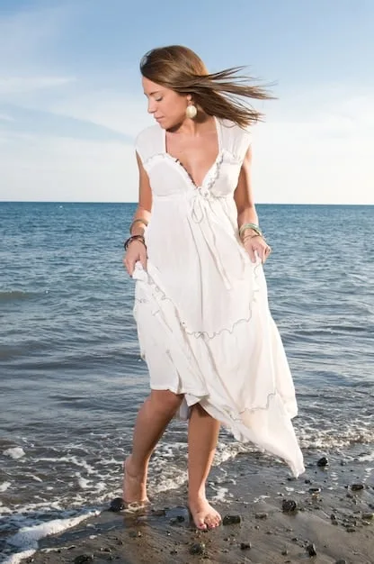 A woman wearing a flowing floral maxi dress with strappy sandals at a beach wedding. The dress is light and airy, perfect for the ocean breeze, and the sandals are practical for walking on the sand.