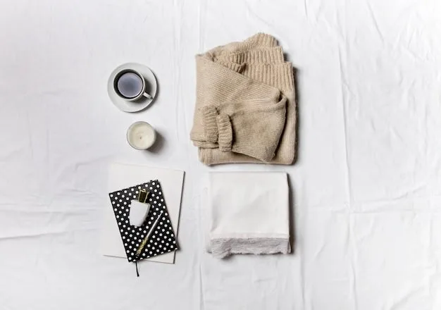 A close-up of a neatly folded stack of essential weekend clothing items, including a white cotton t-shirt, a pair of medium-wash denim jeans, a light grey cotton sweater, and a pair of white canvas sneakers.