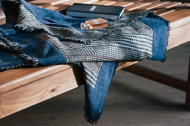 A close-up shot of several layered clothing items laid out on a bed, including a denim jacket, a flannel shirt, a basic white tee, and a lightweight scarf.
