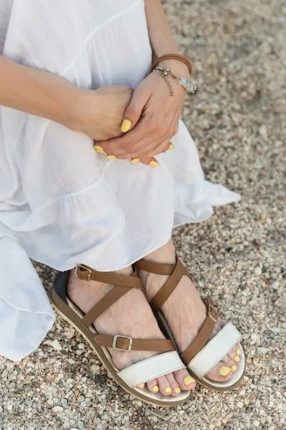 A close-up shot of minimalist sandals in neutral tones (white, beige, tan). Focus on the clean lines, simple straps, and quality of materials like leather or sustainable alternatives. Show the sandals on a clean, light background to emphasize their understated elegance.