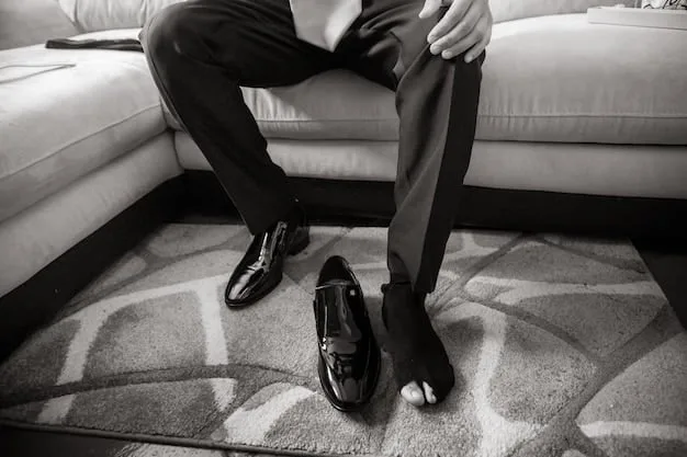 A close-up shot of a pair of well-tailored black trousers with a slight crease, paired with elegant black loafers and a simple leather belt. The background is a minimalist, modern interior.