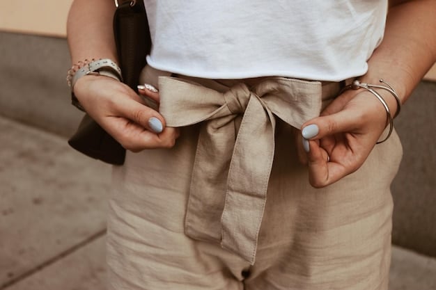 A close-up shot of a woman's hands accessorizing a neutral outfit. She is adding a colorful scarf to a beige trench coat, with a stack of bangles on her wrist. The background is softly blurred, showcasing a rack of neutral-colored clothing, emphasizing the versatility of a neutral-based wardrobe. The lighting is soft and diffused, focusing on the textures of the scarf and coat.