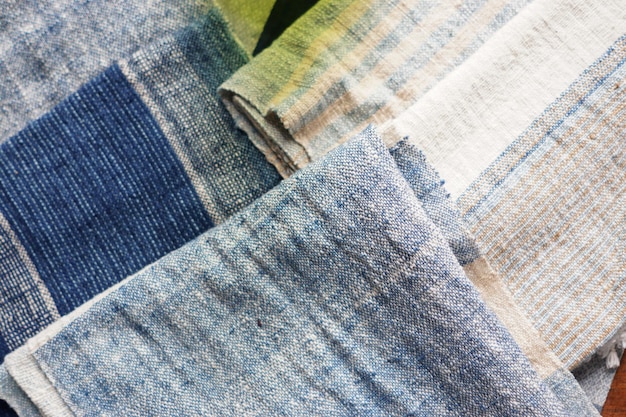 A close-up shot of various sustainable fabric swatches, including organic cotton, recycled denim, and hemp. The fabrics have a natural, raw texture that highlights their eco-friendly origins. The lighting is soft and emphasizes the textures and subtle colors of the materials.