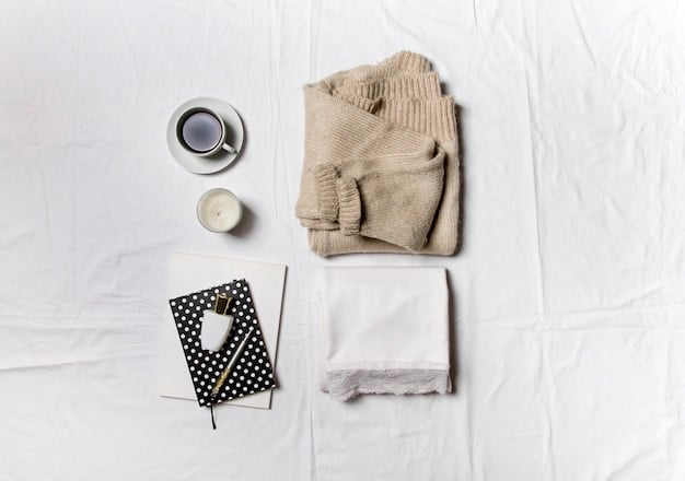 A close-up of a neatly folded stack of essential weekend clothing items, including a white cotton t-shirt, a pair of medium-wash denim jeans, a light grey cotton sweater, and a pair of white canvas sneakers.