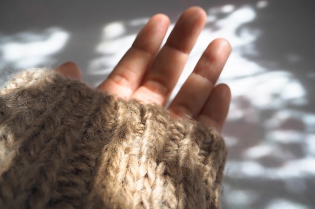 A detailed shot of a hand gently touching a knitted alpaca scarf. The focus is on the texture of the material, highlighting its softness and natural sheen. The hand is well-manicured and the lighting emphasizes the warmth and comfort associated with the scarf.