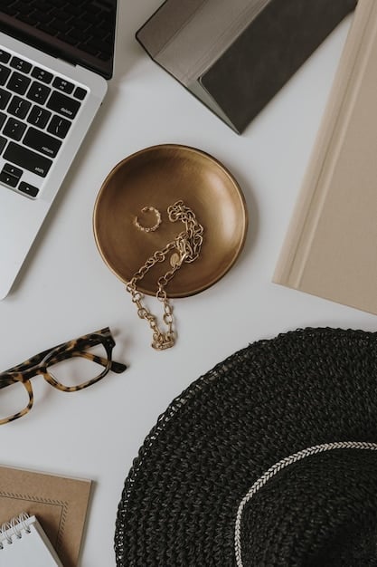 A stylish, organized desk featuring minimalist gold jewelry (necklace, bracelet, rings), a structured leather tote bag, and a pair of classic, pointed-toe pumps. The background is a clean, modern office space with natural light.