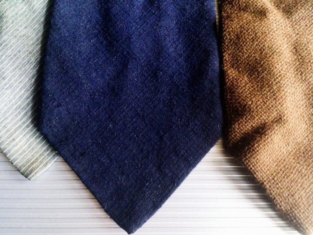 A close-up shot of various fabric textures used for layering, including cashmere, denim, cotton, and wool. The image emphasizes the importance of selecting comfortable and breathable materials for transitional dressing.