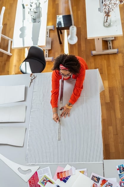 A designer in their studio, surrounded by fabric samples and sketches, working on a new menswear piece. The atmosphere is creative and focused, showing the intersection of traditional techniques and innovative materials.