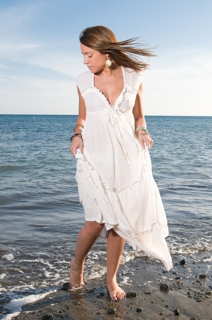 A woman wearing a flowing floral maxi dress with strappy sandals at a beach wedding. The dress is light and airy, perfect for the ocean breeze, and the sandals are practical for walking on the sand.