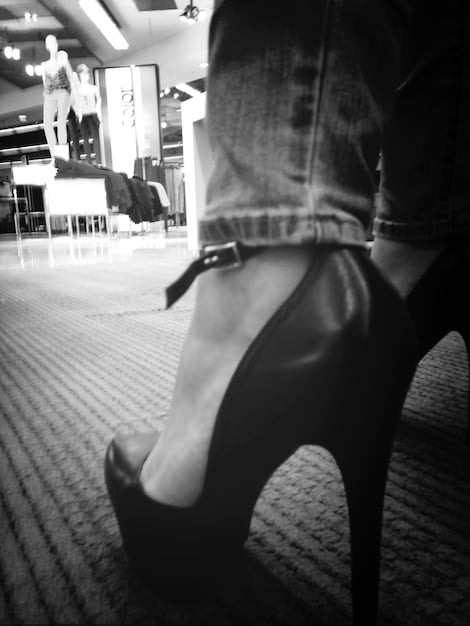 A close-up shot of a pair of classic black high heels. The focus is on the elegant curve of the heel and the polished finish of the shoe.