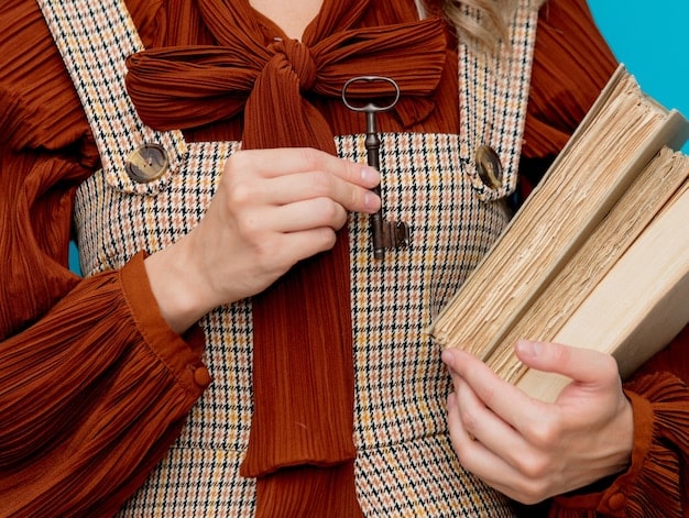 A close-up shot of a woman's hands inspecting the stitching and fabric of a vintage dress in a dimly lit vintage shop. The focus is on the details of the garment's construction.