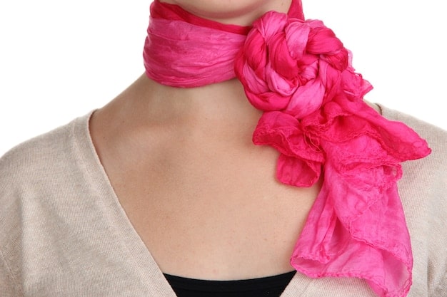 A close-up shot of a woman's neck showing a silk scarf tied in a Parisian knot, showcasing the elegant folds and texture of the fabric.