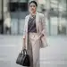 Woman elevating outfit with statement necklace, structured handbag, and modern watch